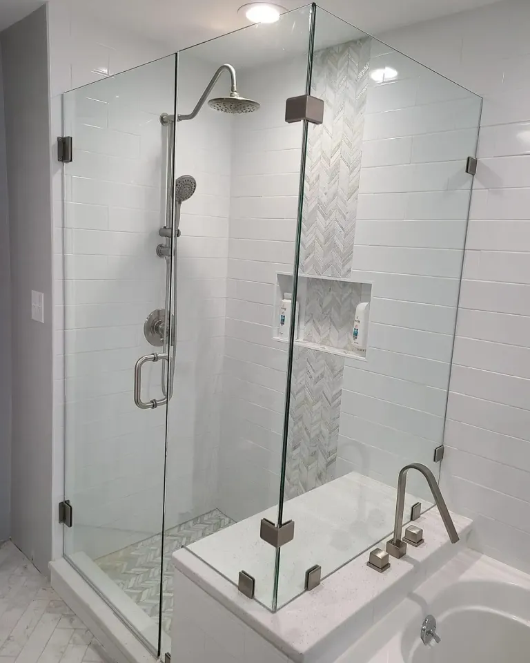 Close view of shower door glass, hinge, and seal area