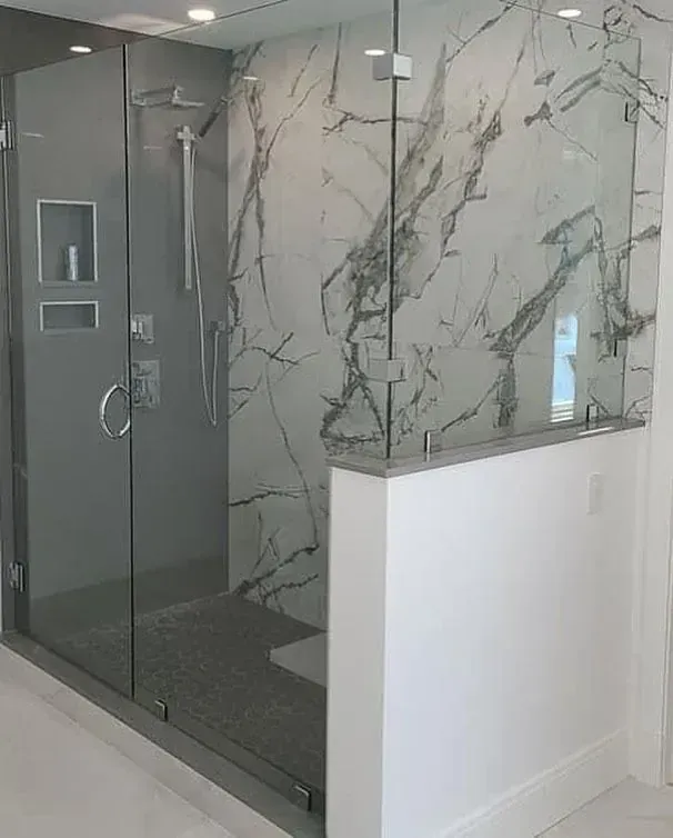 Corner shower glass beside marble-patterned tile