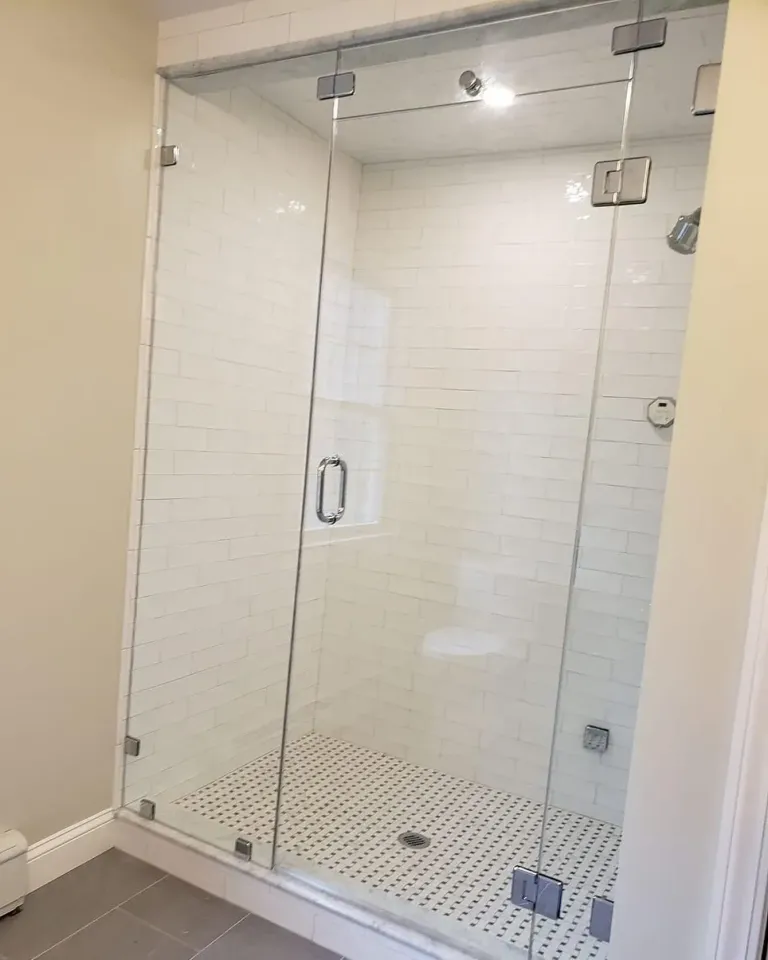 Hinged shower door below a fixed glass panel