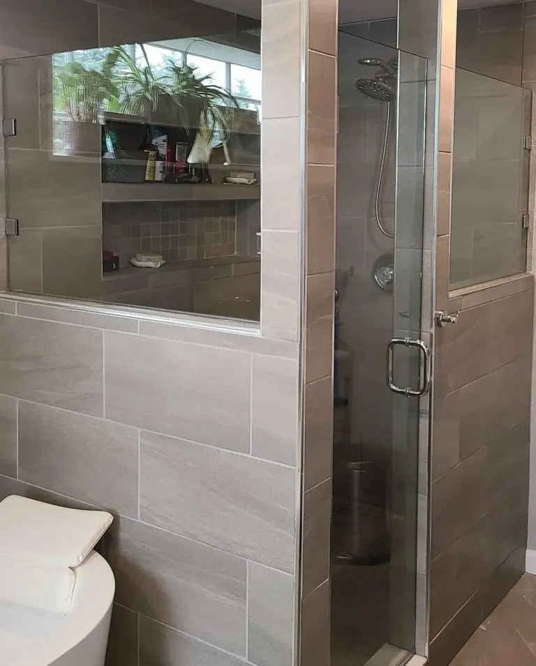 Hinged shower door beside a tiled half wall