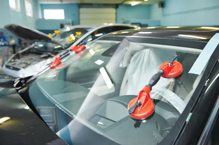 Windshield installation tools positioned on vehicles inside an auto glass shop