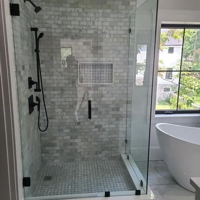 Shower enclosure with dark hinges beside a tub